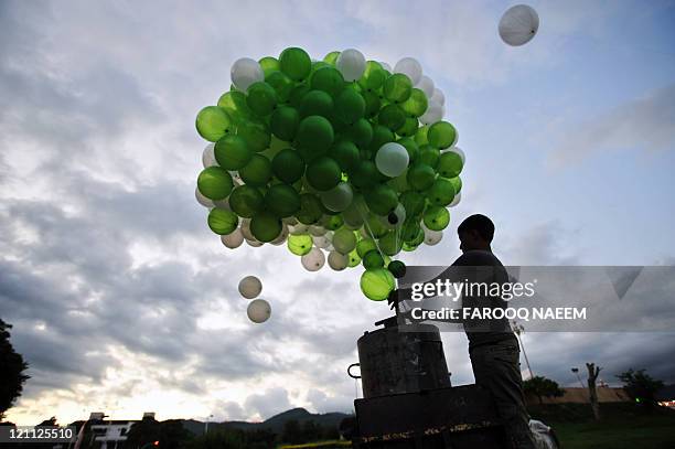 Pakistani boy inflates green and white balloons, the colours of Pakistan's national flag, near the parliament building in Islamabad on August 13,...