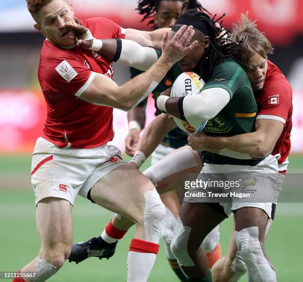 Connor Braid and Harry Jones of Canada try to tackle Branco du Preez of South Africa during their bronze medal rugby sevens game at BC Place on March...