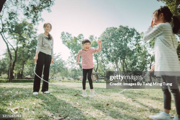 mom & daughters jumping ropes joyfully on the lawn - asian games day 9 stock-fotos und bilder