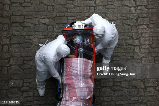 Medical staff, wearing protective gear, move a patient infected with the coronavirus from an ambulance to a hospital on March 09, 2020 in Seoul,...