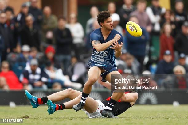 Brandon Parfitt of the Cats handpasses the ball whilst being tackled Mason Redman of the Bombers during the Marsh Community Cup AFL match between the...