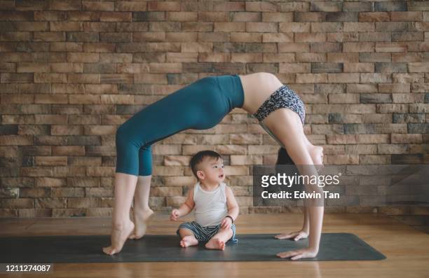 an asian chinese female yoga instructor with bridge pose while her son looking at her - female muscle calves stock pictures, royalty-free photos & images