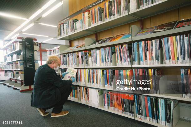 Visitor, with face mask and gloves search for the magazine inside the city center library of in Cologne, Germany on April 29 after city takes much...