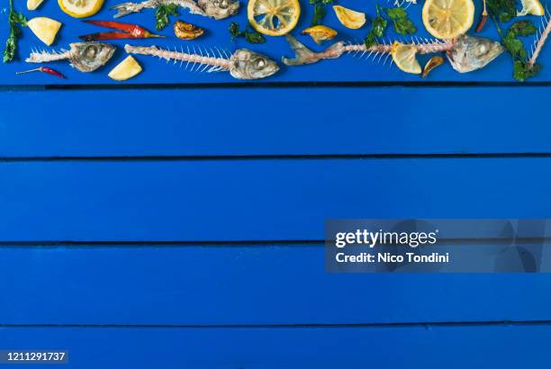 fish bones of oily fish: atlantic horse mackerel, mackerel,  anchovies, sardines on a blue  wooden background - trachurus trachurus stock-fotos und bilder