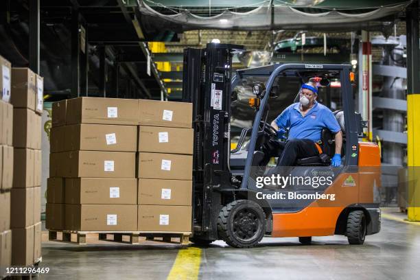 Worker wearing a protective face mask operates a forklift to move boxes of face shields ready for shipment at the Cartamundi-owned Hasbro...