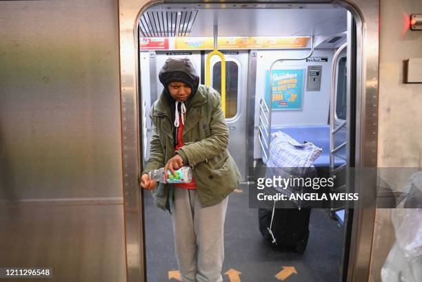 Woman washes her hands outside a subway train on April 29, 2020 in New York City. - New York Citys homeless have sought refuge in the subways to...