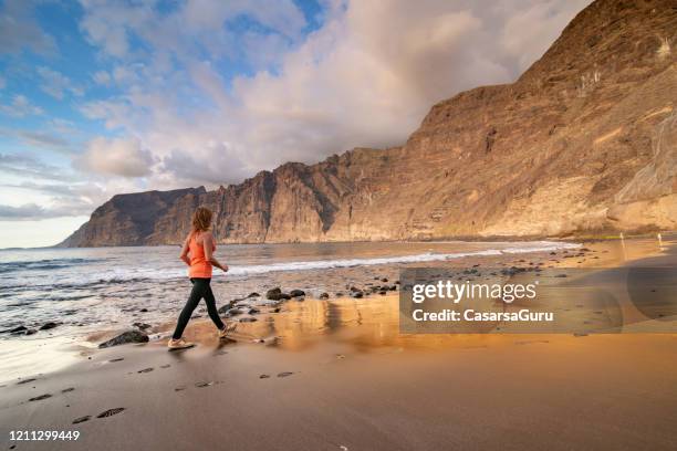 reife erwachsene frau training am strand von playa de los gigantes, kanarische insel teneriffa, spanien - stockfoto - tenerife stock-fotos und bilder