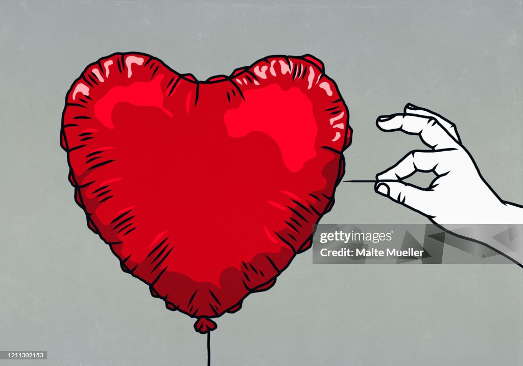 Hand with pin ready to pop red heart shape balloon