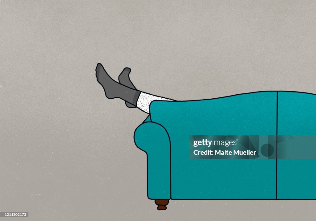 Legs of man in socks dangling off sofa