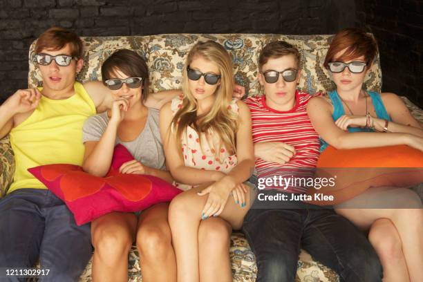 portrait cool teenagers in sunglasses on sofa at party - teenage girl club stock-fotos und bilder