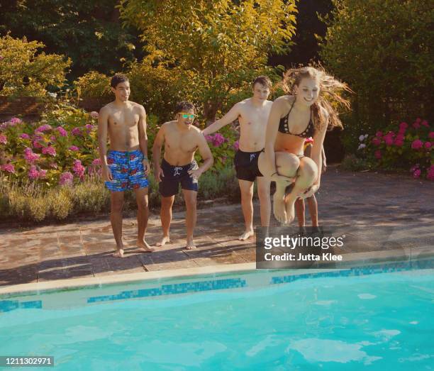 teenage girl cannonball diving into summer swimming pool - arschbombe stock-fotos und bilder
