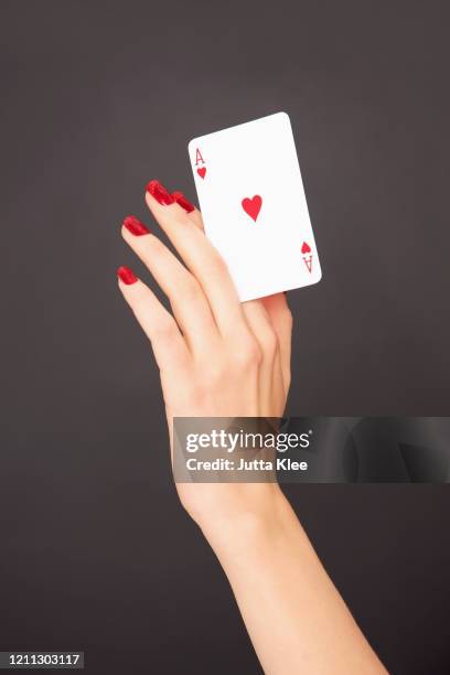 portrait woman with red fingernails holding ace of hearts card - red nail polish stockfoto's en -beelden