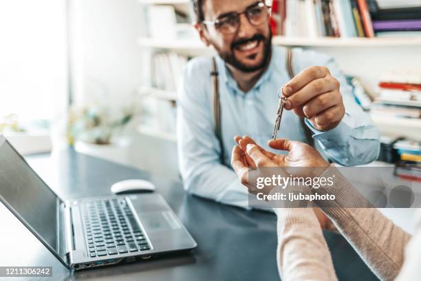 real estate agent passing keys to his client - passing giving stock pictures, royalty-free photos & images