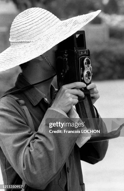 Un touriste chinois portant un chapeau de paille prend une photo avec un appareil bi-ojectif en 1979 en Chine.