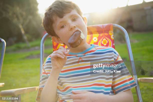 portrait boy eating chocolate ice cream bar on summer patio - sun flare on glass bildbanksfoton och bilder