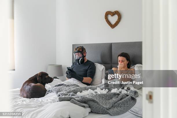 couple in bed. wife has the flu. husband isn't taking any risks..! - liens relationels photos et images de collection