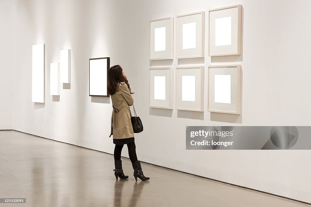 One woman looking at white frames in an art gallery