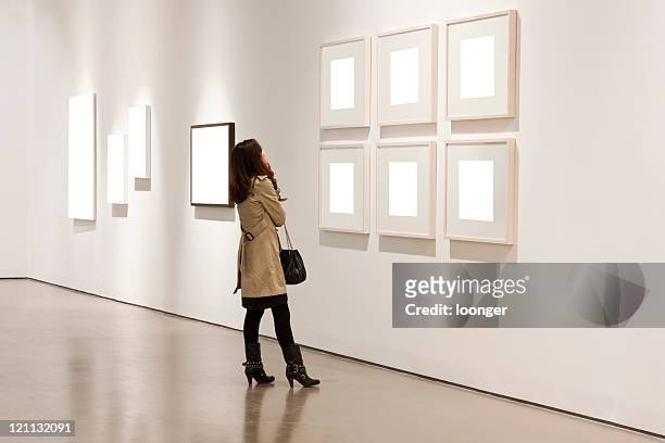 one woman looking at white frames in an art gallery - exhibition stock pictures, royalty-free photos & images