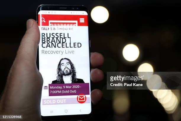 In this photo illustration the web page for the Perth Concert Hall is displayed on a mobile phone advising of the cancelled Russell Brand show on...