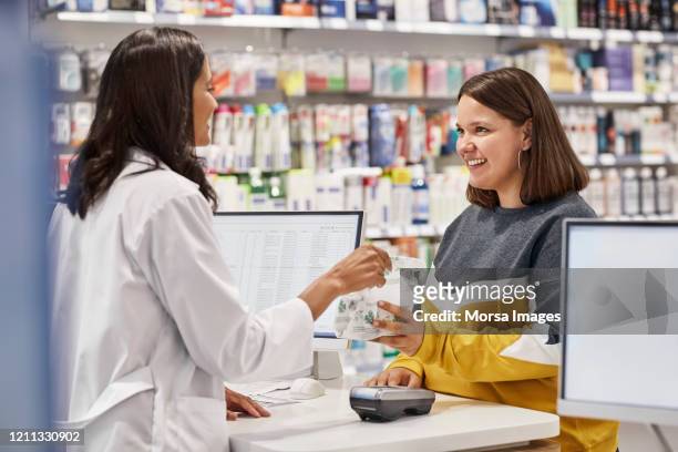 happy woman taking medicine from cashier - farmacia fotografías e imágenes de stock