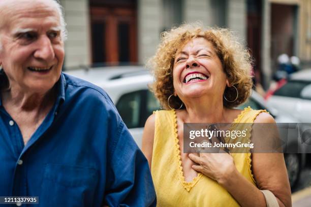 femme aînée hispanique riant tout en conversant avec le mari - couple de vieux drole photos et images de collection