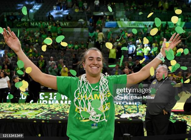 Sabrina Ionescu of the Oregon Ducks wears a basketball net around her neck and throws confetti in the air as she celebrates her team's 89-56 win over...