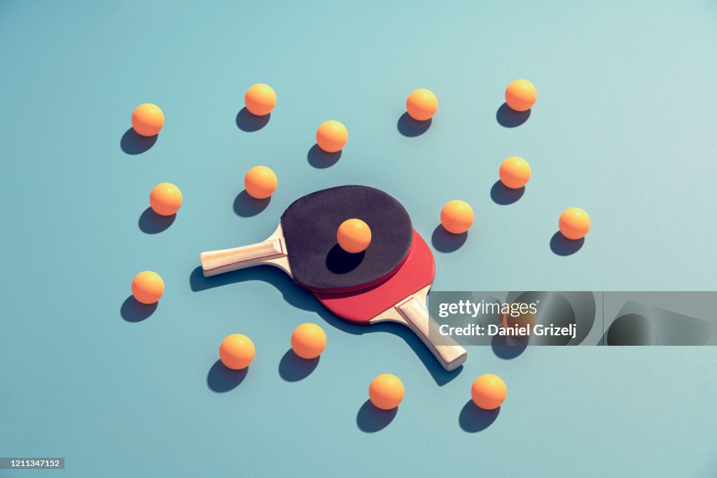 Table tennis rackets surrounded by yellow ping pong balls