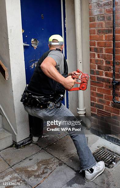 Metropolitan police officers force entry through the front door of a property in Brixton during an early morning raid in connection with recent...