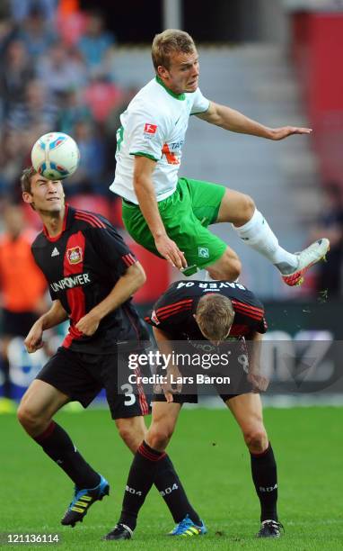 Lennart Thy of Bremen jumps over Stefan Reinartz and Lars Bender of Leverkusen during the Bundesliga match between Bayer 04 Leverkusen and SV Werder...