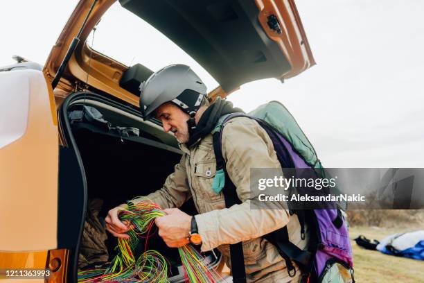 senior man packing up his parachute - motor paraglider stock pictures, royalty-free photos & images