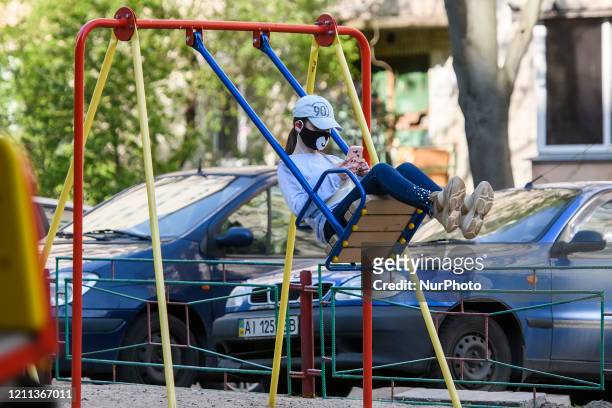 The girl in a protective mask swings on the playground, amid the coronavirus disease COVID-19 outbreak in Kyiv, Ukraine on April 29, 2020