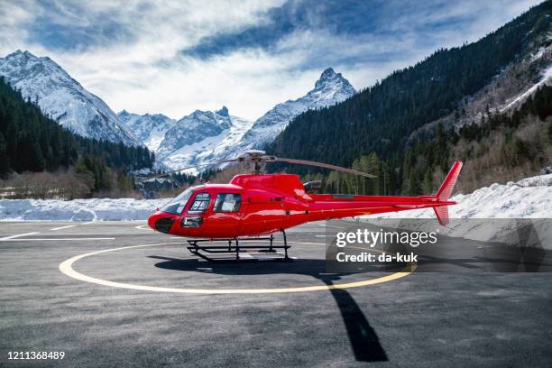 roter hubschrauber in den bergen - hubschrauber landeplatz stock-fotos und bilder