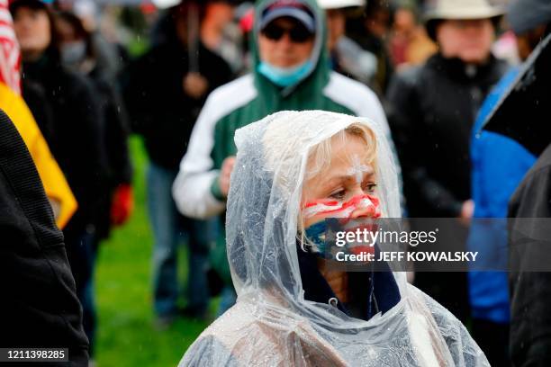 Protestor with an upside down flag painted on her face stands at an American Patriot Rally organized by Michigan United for Liberty protest for the...