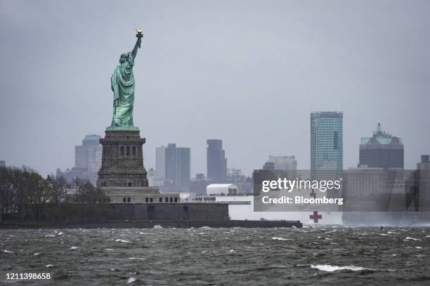 The USNS Comfort hospital ship sails past the Statue of Liberty with the South Brooklyn Skyline as seen from across the Hudson River in Jersey City,...