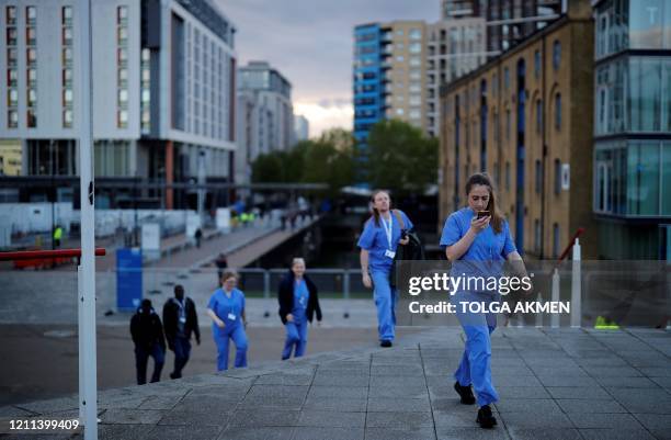 Medical staff from Britain's NHS in scrubs walk outside the ExCeL London exhibition centre, which has been transformed into the "NHS Nightingale"...