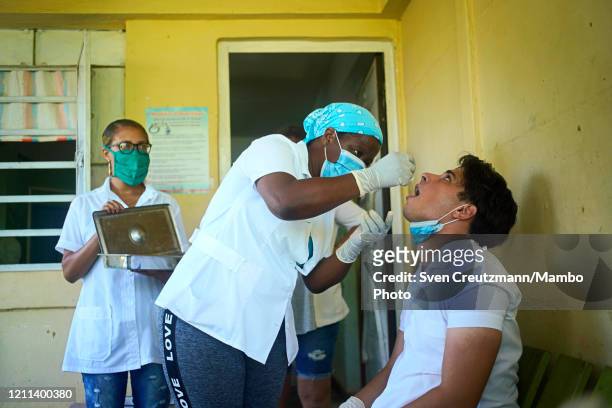 Cuban nurse administers Prevengho-Vir, a Cuban homeopathic product, to a medicine student as a protective measure at the family doctors office during...