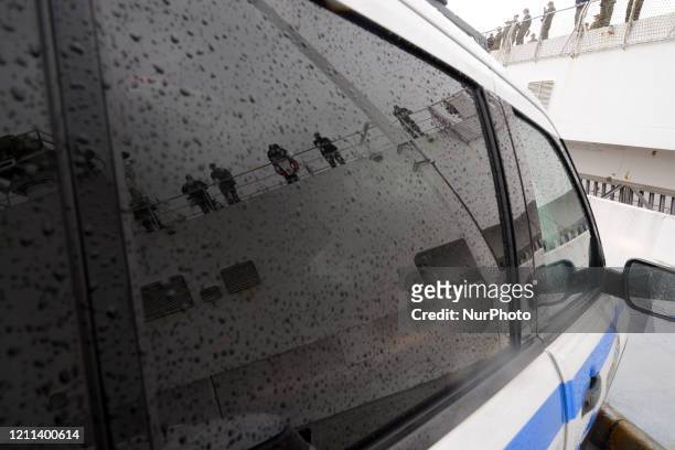 Reflections of U.S. Navy medical personnel manning the rails of the hospital ship Comfort are seen in the reflection of a waiting NYPD cruiser as the...
