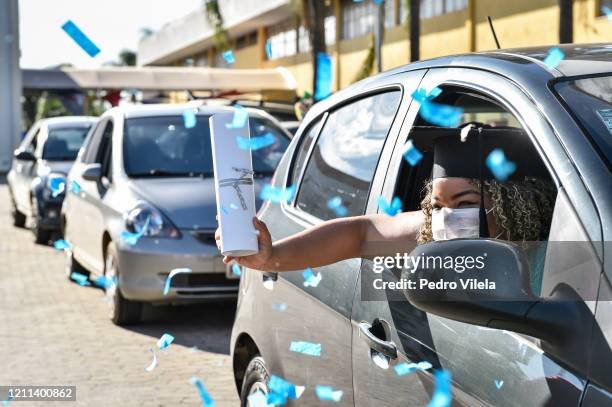 Graduate from the medical and nursing school of Faseh University celebrates from a car after receiving the diploma during a drive-thru ceremony to...