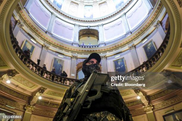 An armed protester wearing a mask stands at the Michigan Capitol Building in Lansing, Michigan, U.S., on Thursday, April 30, 2020. Protesters...
