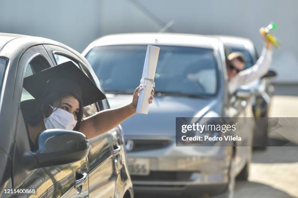 Graduate from the medical and nursing school of Faseh University celebrates from a car after receiving the diploma during a drive-thru ceremony to...