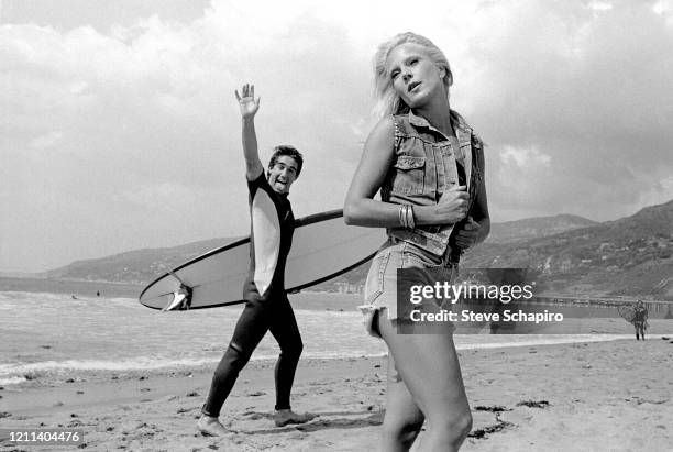 Bulgarian-born French singer and actress Sylvie Vartan, in a cut-off jean jacket and denim shorts, poses as an unidentified surfer, waving and...