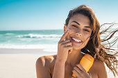 Smiling woman applying sunscreen