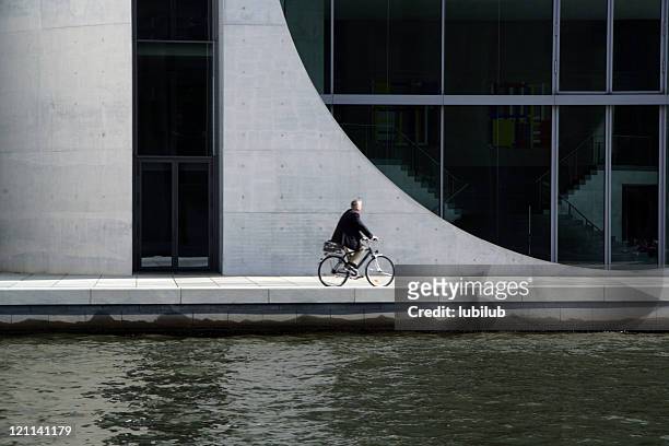 man on bicycle in berlin by river spree, germany - concrete architecture stock pictures, royalty-free photos & images