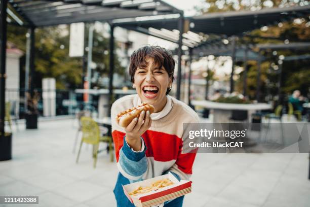 jovem mulher comendo fast food - hot dog - fotografias e filmes do acervo