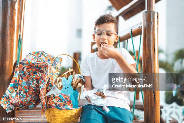 little boy eating easter egg in public park - gourmet gift basket stock pictures, royalty-free photos & images