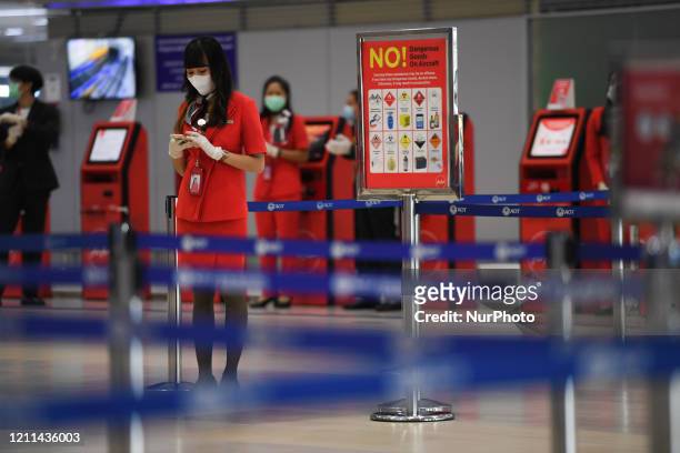 Cabin crew of Air Asia wearing a face mask and gloves at check-in counter of erminal 2 Don Mueang airport on May 1, 2020 in Bangkok, Thailand. As...