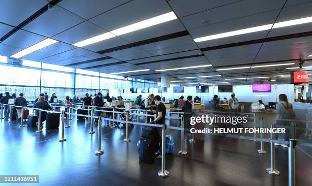 Flight passengers queue at a check in desk of the low-cost airline Wizz Air on May 1, 2020 at the Schwechat airport near Vienna, Austria. - Wizz Air...