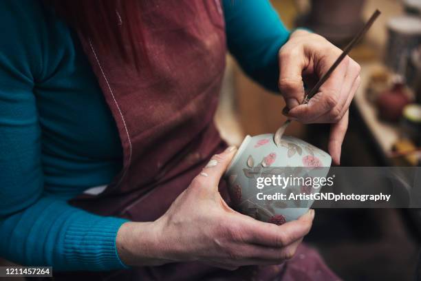 potter feminino irreconhecível decorando um vaso de barro em sua oficina - ceramista - fotografias e filmes do acervo