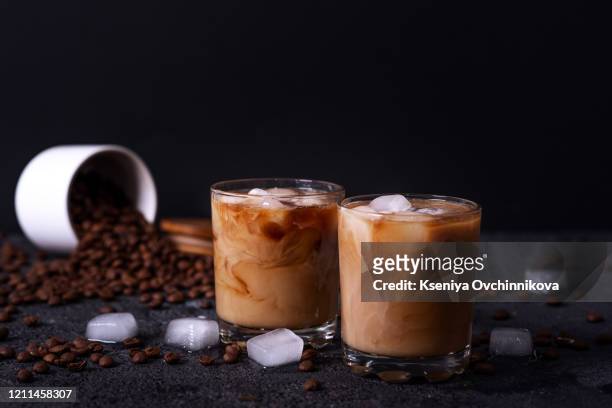 iced coffee in a tall glass with cream poured over - black room stockfoto's en -beelden