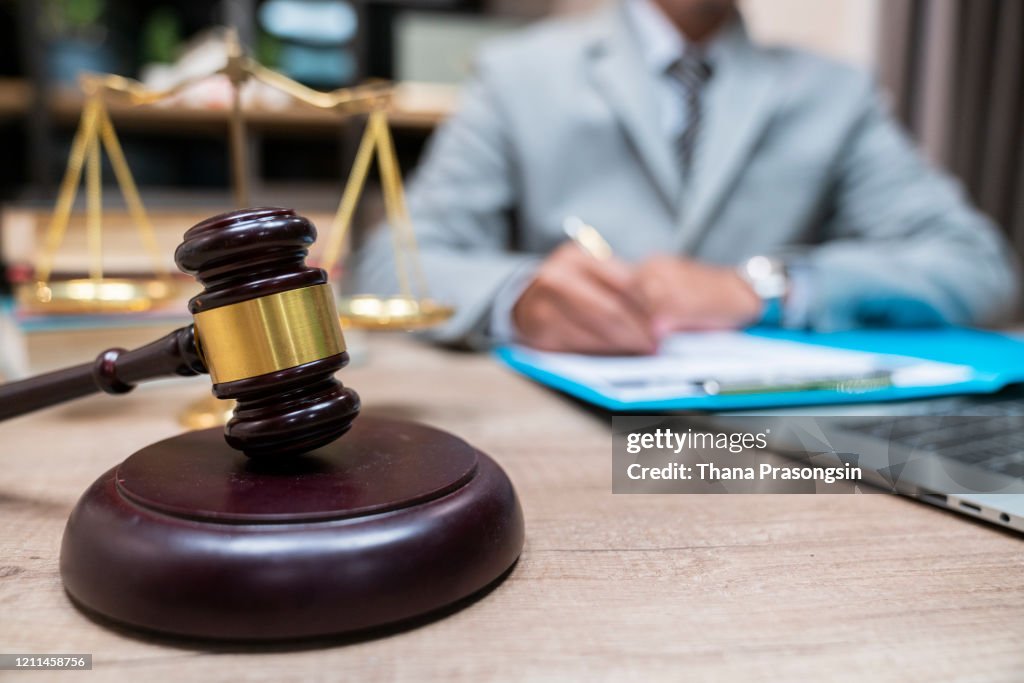 Cropped Hands Of Judge By Gravel At Table